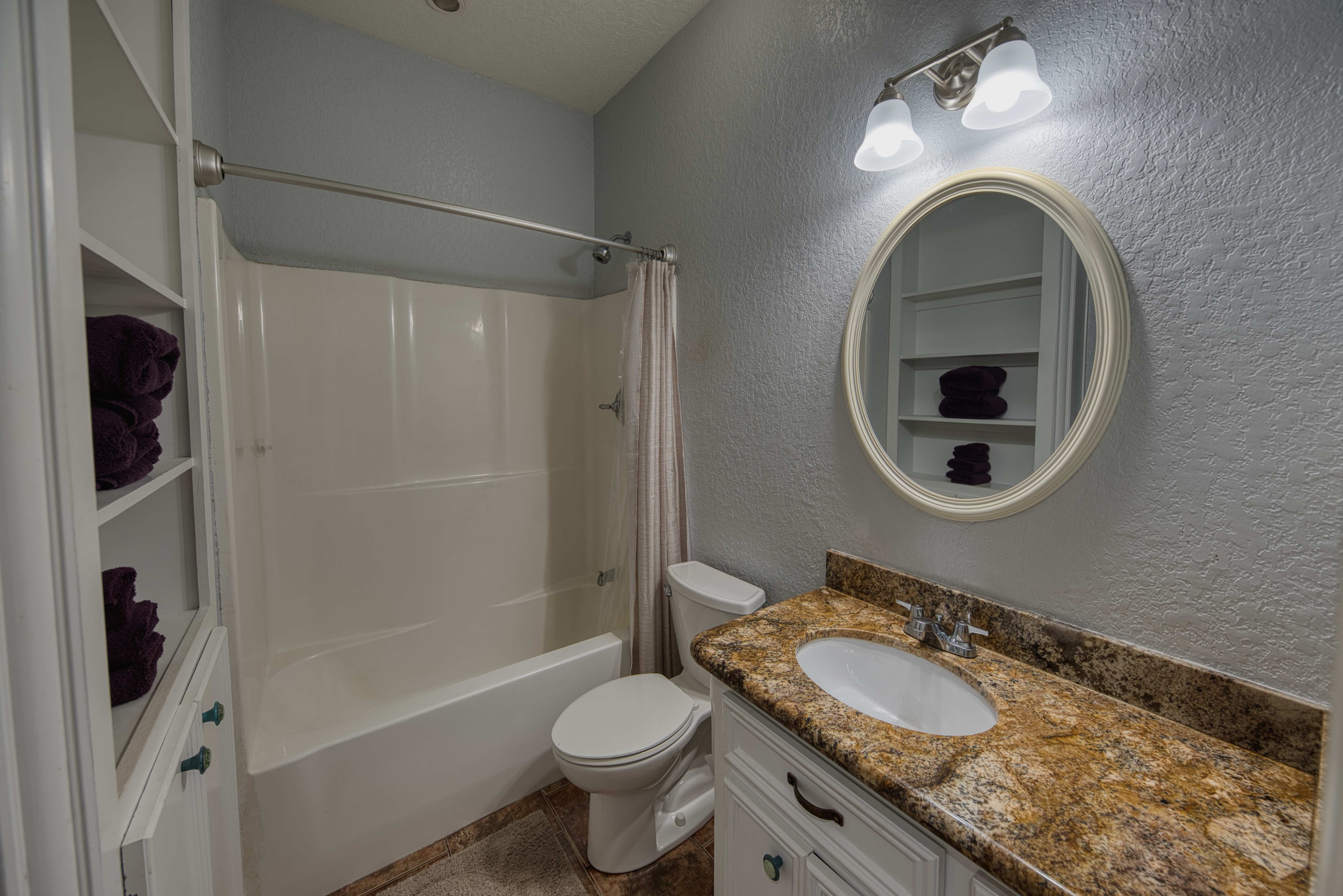 Full bathroom with tub, shower and round mirror