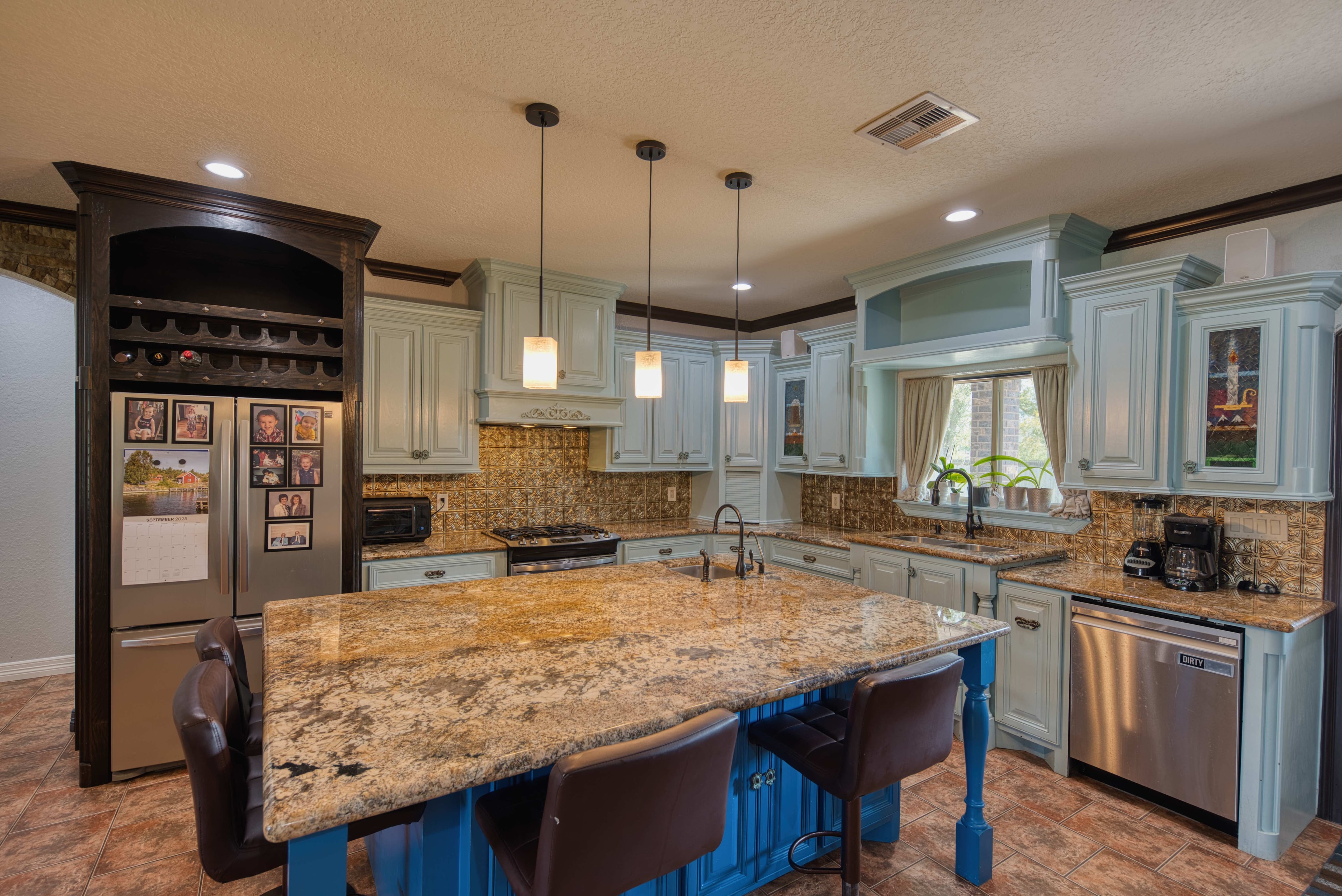 Kitchen with blue island, granite countertops and pendant lighting