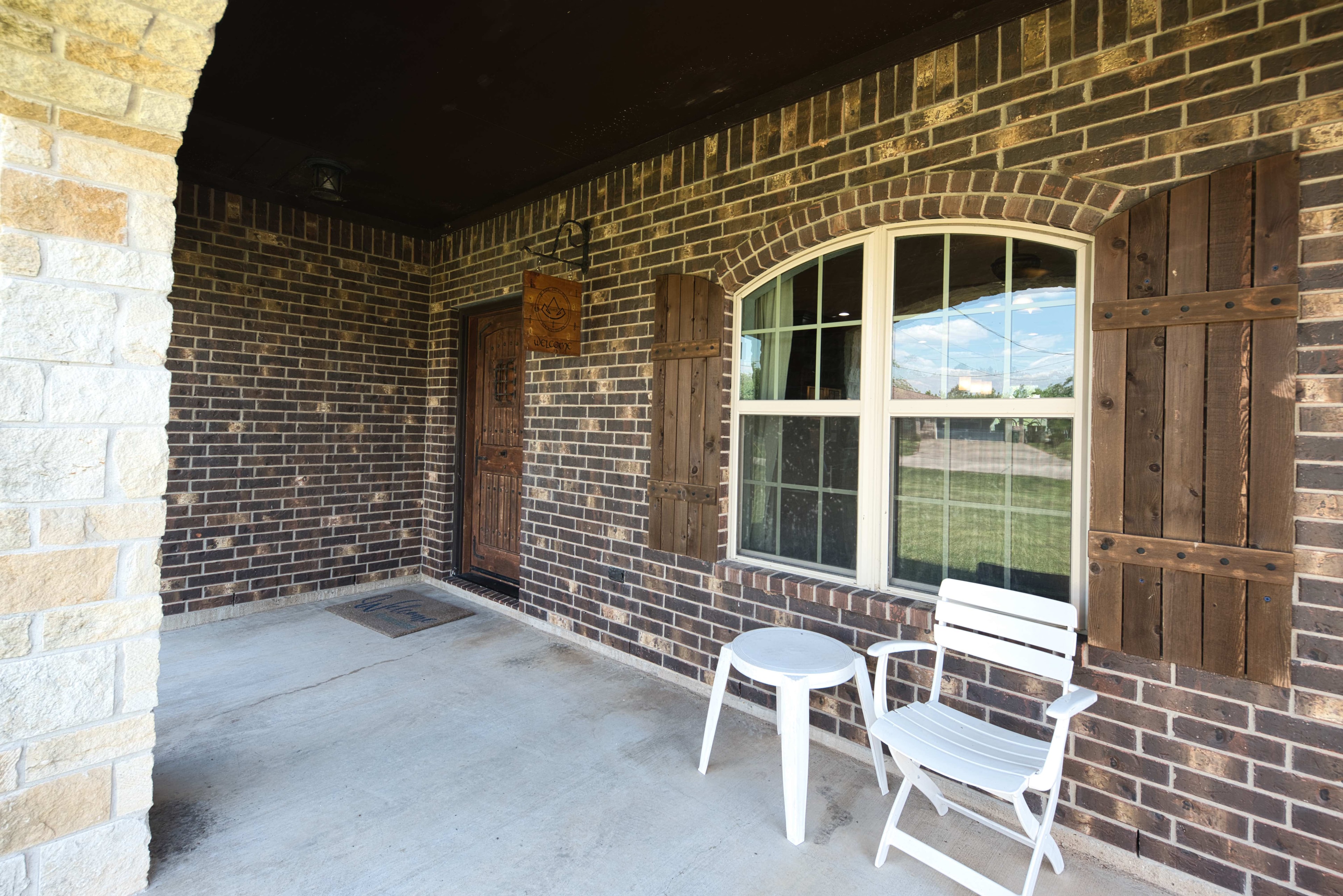Covered front porch with brick and wood shutters